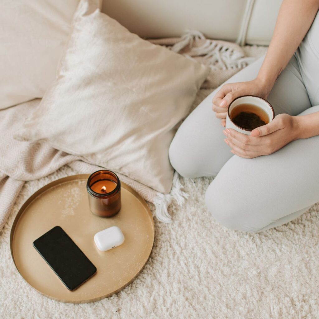 candle and woman holding a cup of tea